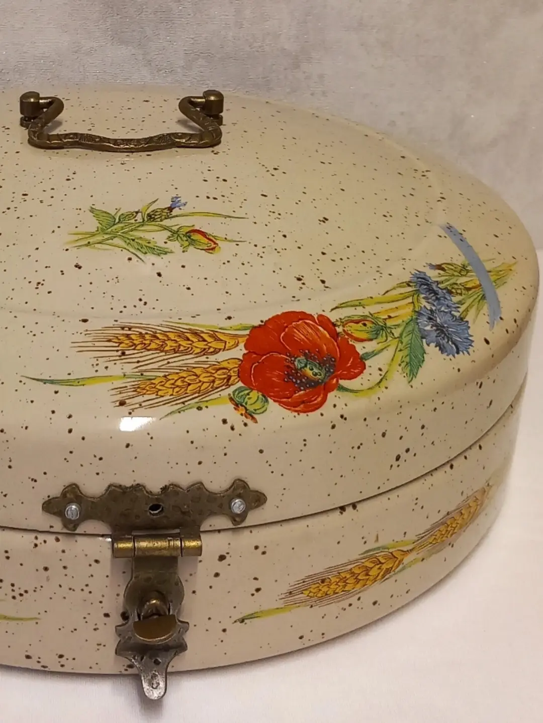 Ekmek kutusu kapağındaki kırmızı gelincik, mavi peygamber çiçeği ve buğday başağı deseninin yakın planı