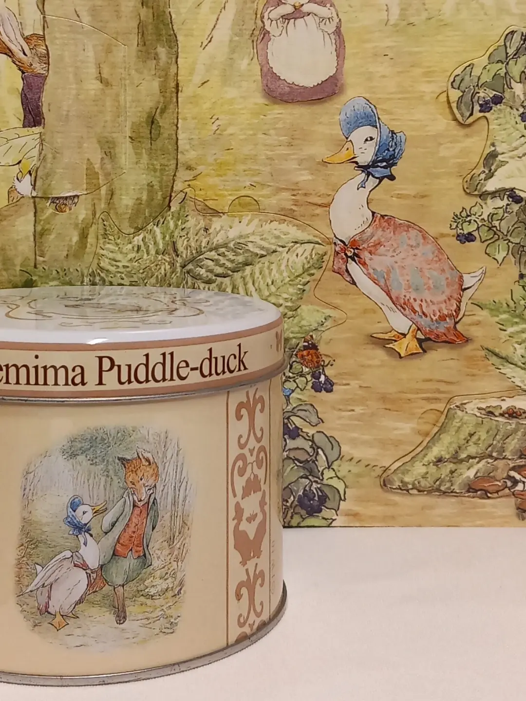 Kutunun tilki ve Jemima illüstrasyonlu yüzü; arkada Jemima figürlü pano