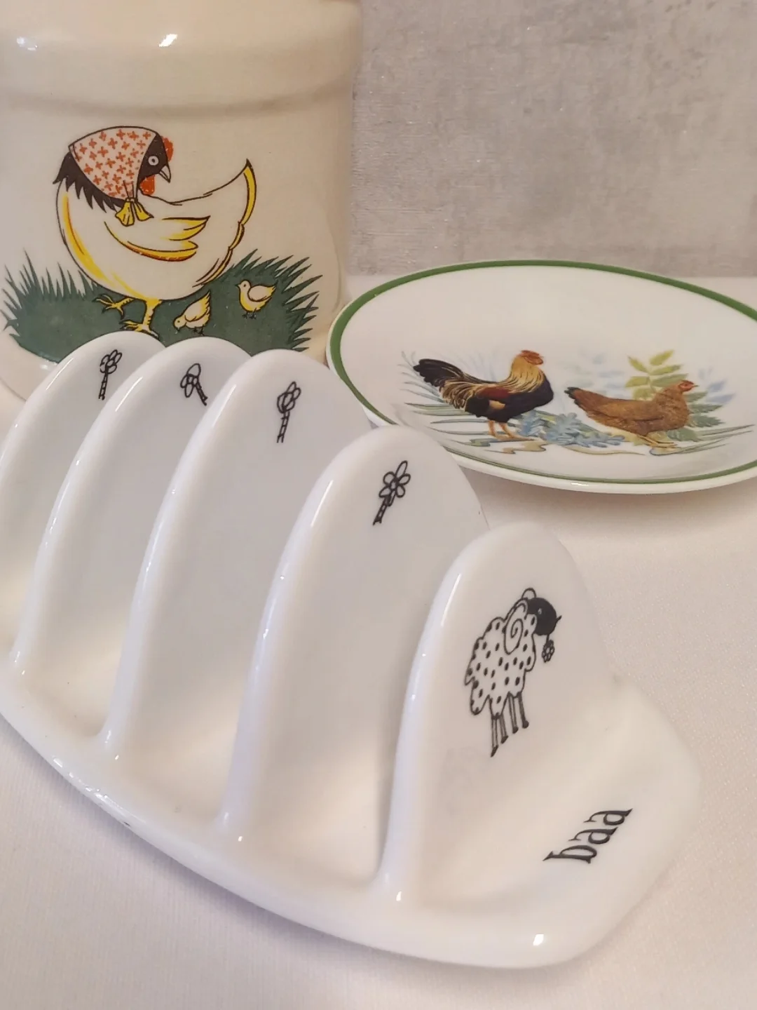 Tabanında 'baa' yazısı ve bölmesinde benekli koyun çizimi bulunan beyaz toast rack'in yakın planı