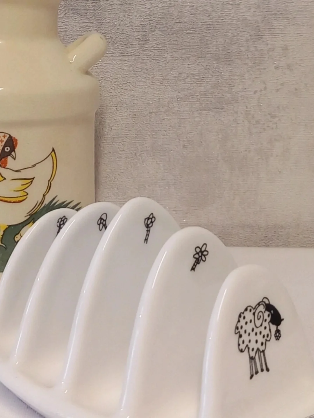 Toast rack bölmelerindeki minik siyah çiçek çizimleri ve koyun figürünün yandan yakın planı