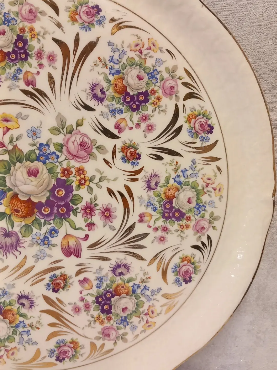 Tabağın sağ yarısında altın yaldızlı yaprak kıvrımları ve çiçek buketleri