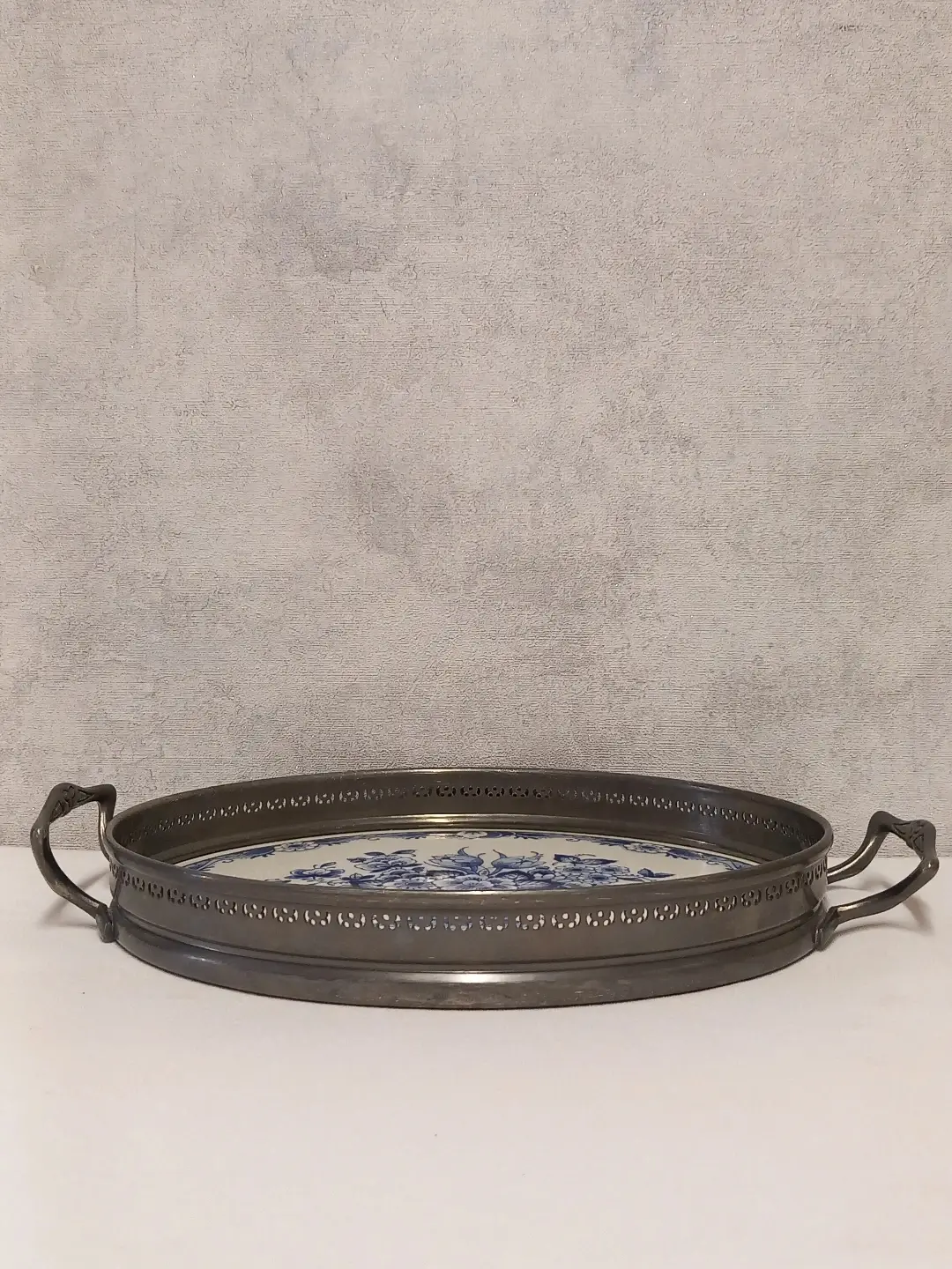 Oval tepsinin delikli metal kenarı ve kulplarıyla yandan görünümü