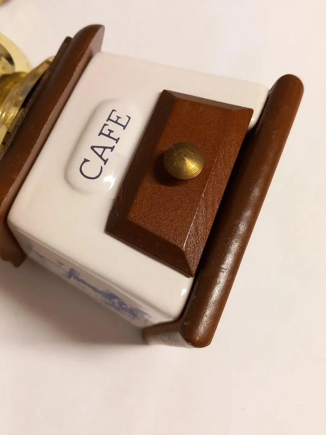 Ahşap çekmece kapağı, pirinç düğme ve CAFE yazılı seramik gövdenin yakın çekimi