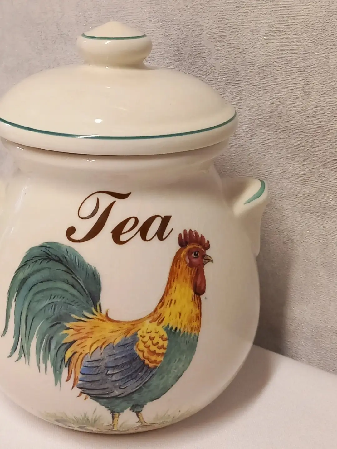 'Tea' yazısı ve yeşil kuyruklu horoz illüstrasyonunun açılı yakın planı