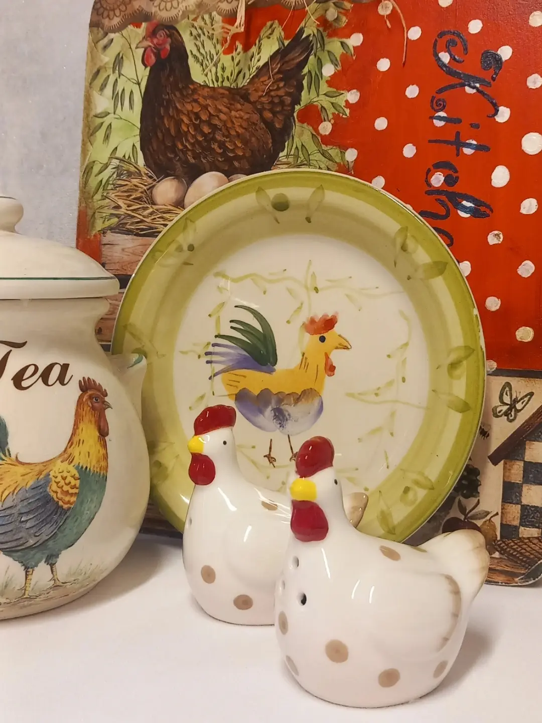 Kahverengi benekli iki beyaz seramik tavuk tuzluk-biberlik; arkada horoz desenli tabak ve çay kavanozu
