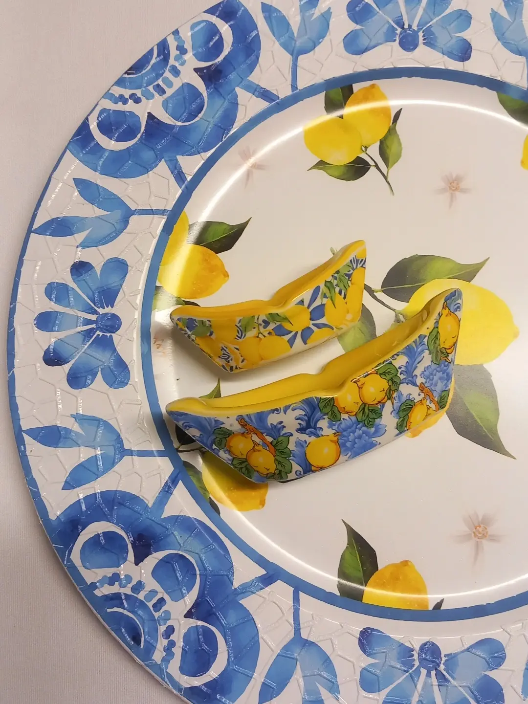 Mavi bordürlü limon desenli büyük tabak üzerinde duran, limonlu iki kayık biçimli mini seramik sabunluk