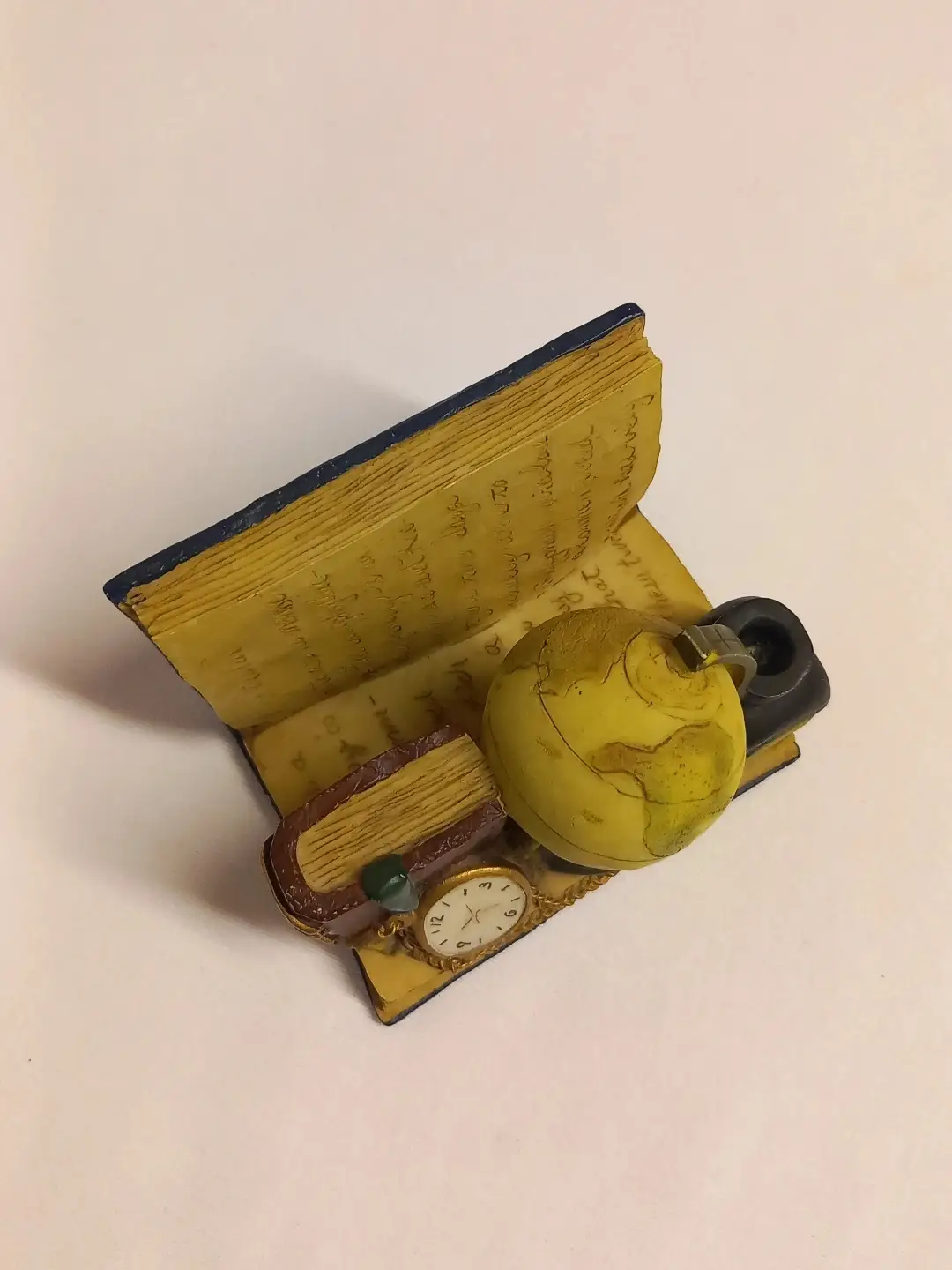 Kitap tutucunun üstten görünümü; yazılı açık kitap sayfaları ve küre