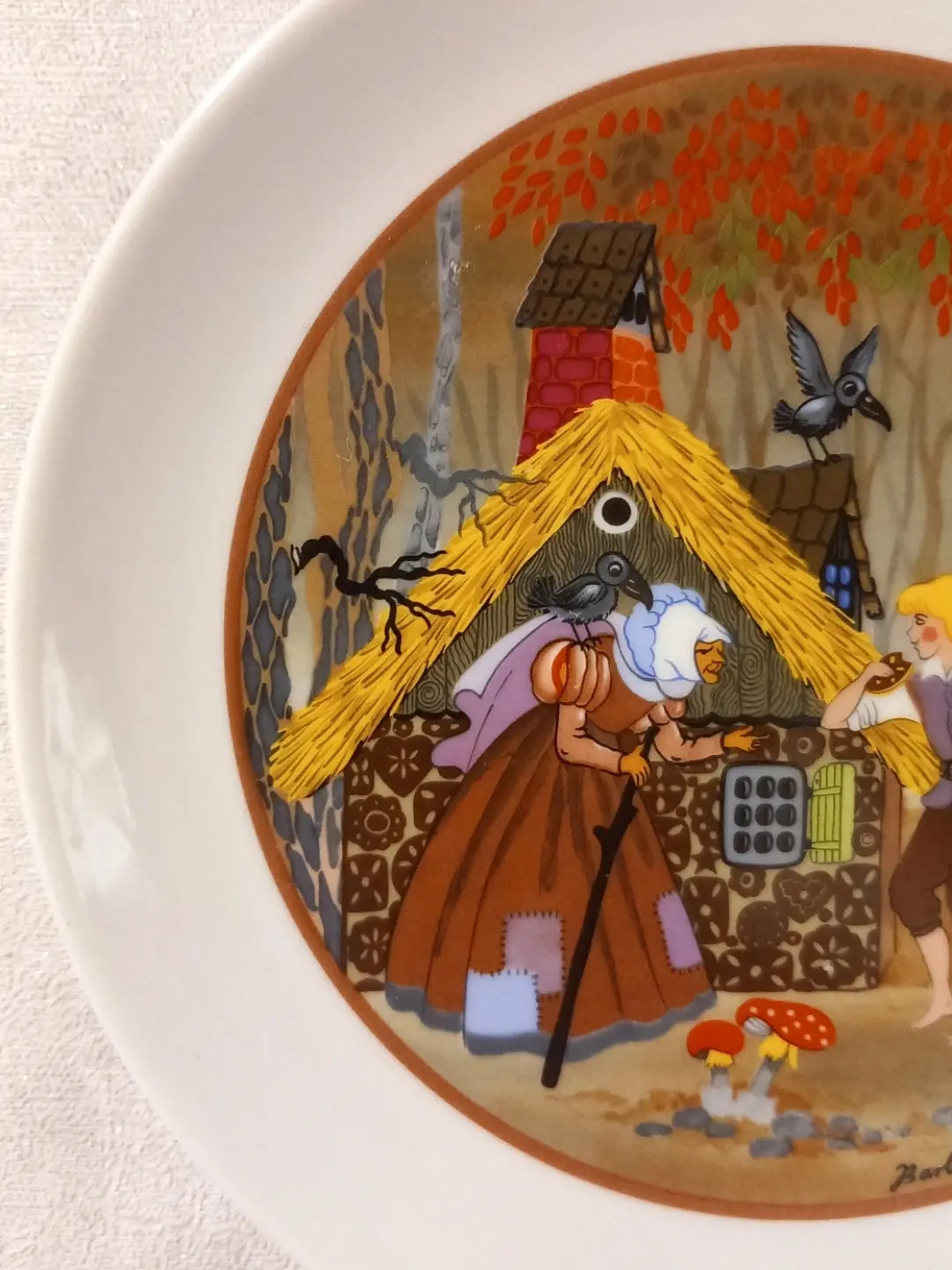 Saman çatılı kurabiye evi ve omzunda karga taşıyan bastonlu cadının yakın planı