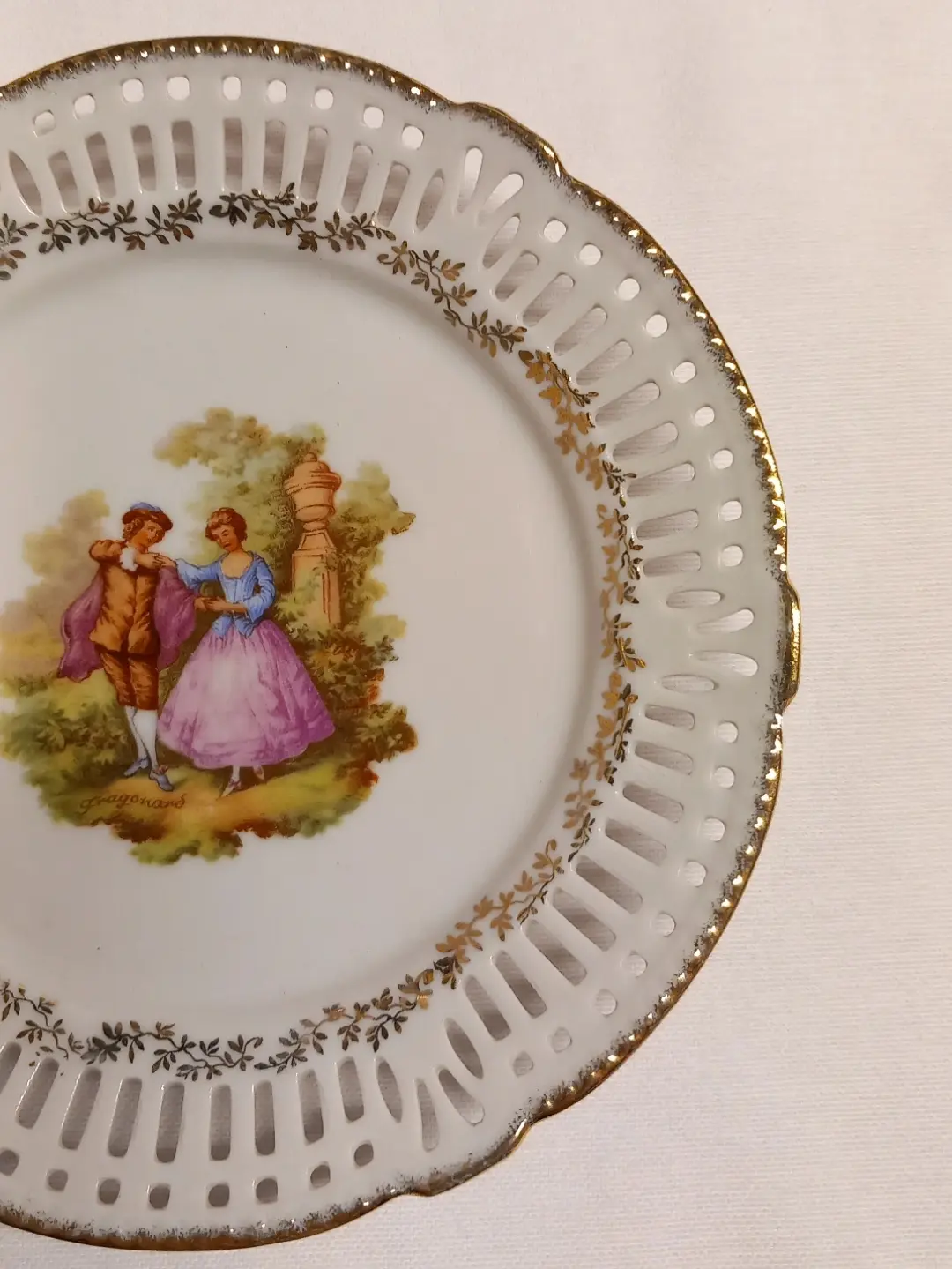Tabağın merkezindeki 'Fragonard' imzalı çift sahnesi ve delikli kenarın yakın çekimi