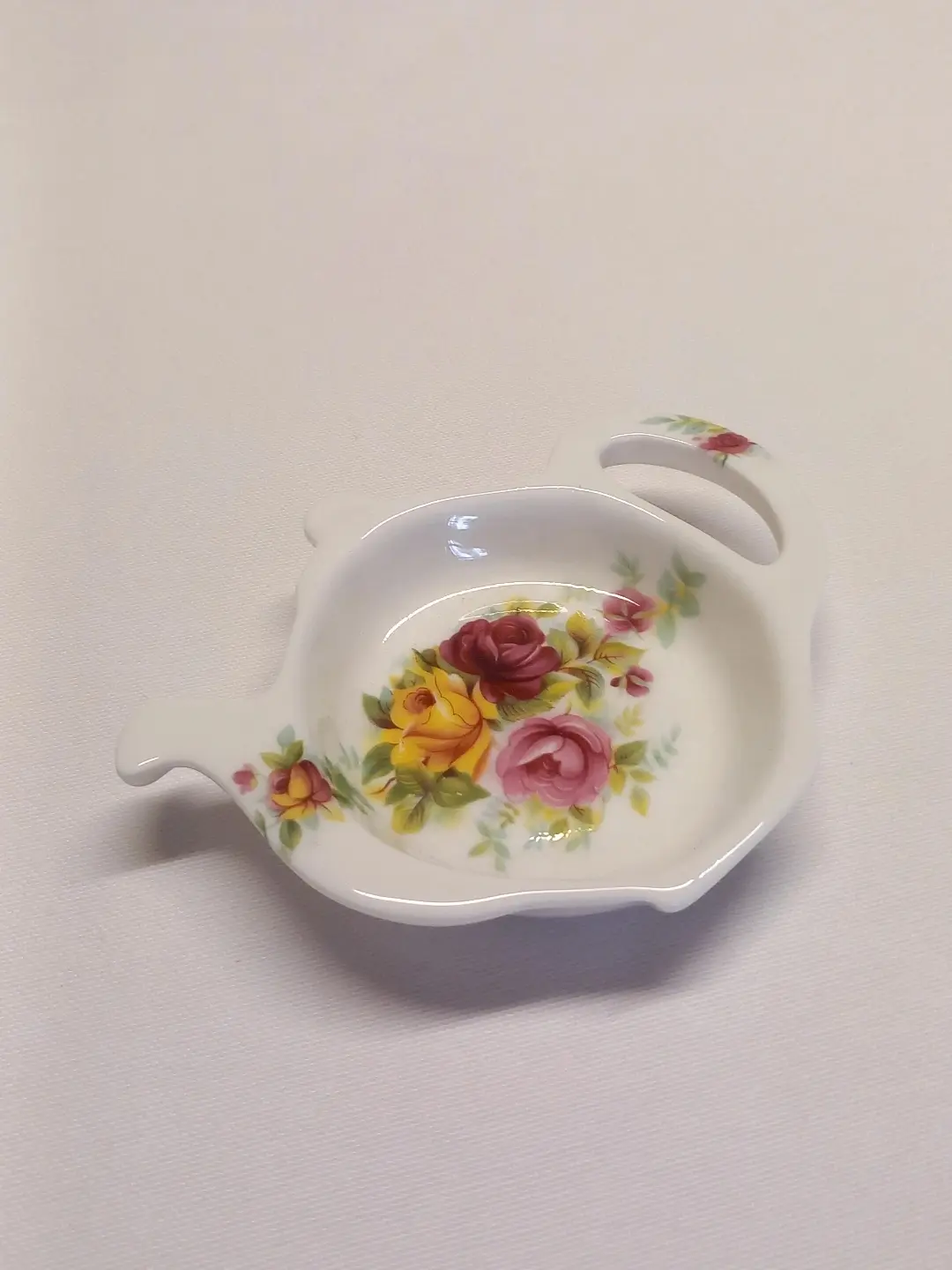 Sarı, pembe ve bordo güllerle bezeli demlik formlu porselen çay poşeti tabağı
