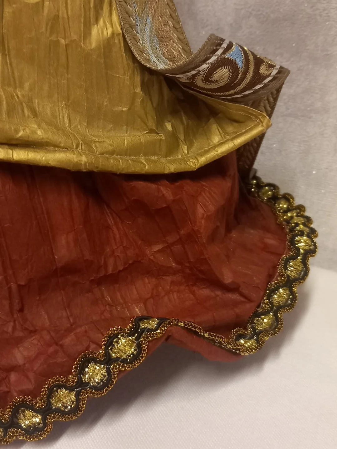 Etek kısmındaki bordo papier-mâché doku ve altın simli şeridin yakın çekimi