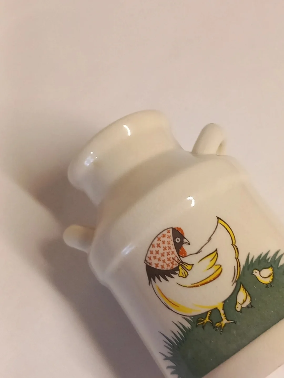 Süt güğümünün ağız kısmı, kulpları ve tavuk deseninin açılı yakın planı