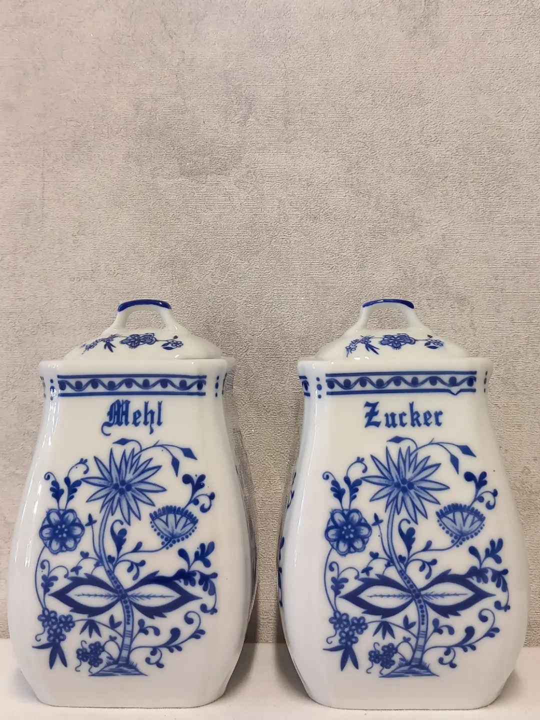 Yan yana 'Mehl' ve 'Zucker' yazılı mavi-beyaz porselen kavanozların önden görünümü